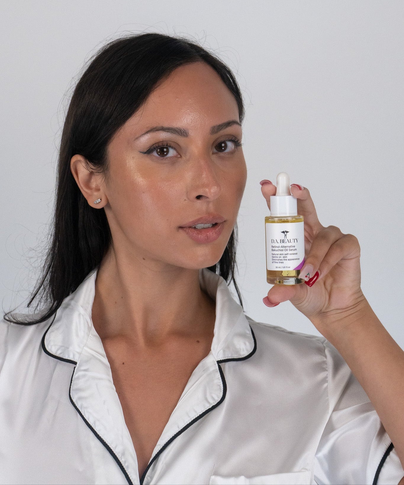 Woman holding a retinol alternative skincare product bottle against a plain background
