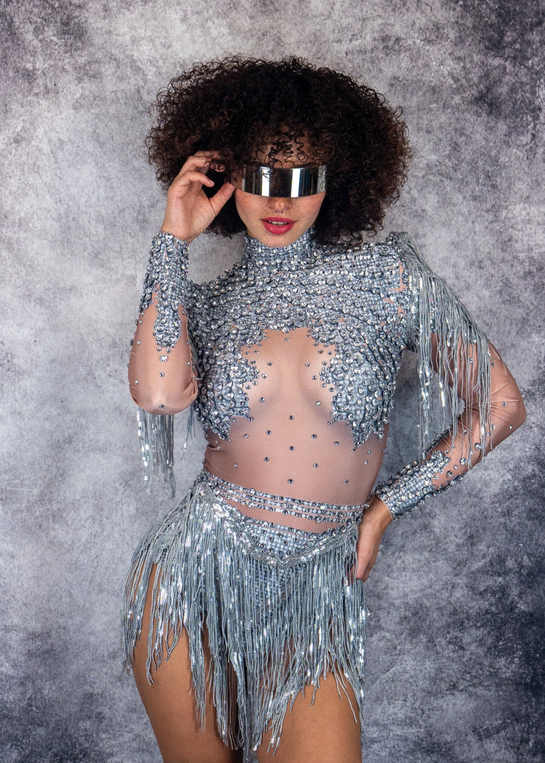 woman wearing a sparkling crystal elegance silver outfit with fringe on a textured gray background