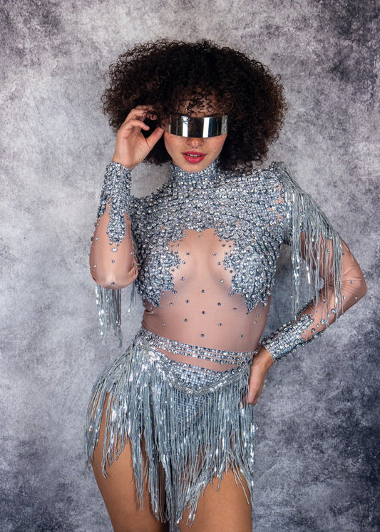 woman wearing a sparkling crystal elegance silver outfit with fringe on a textured gray background