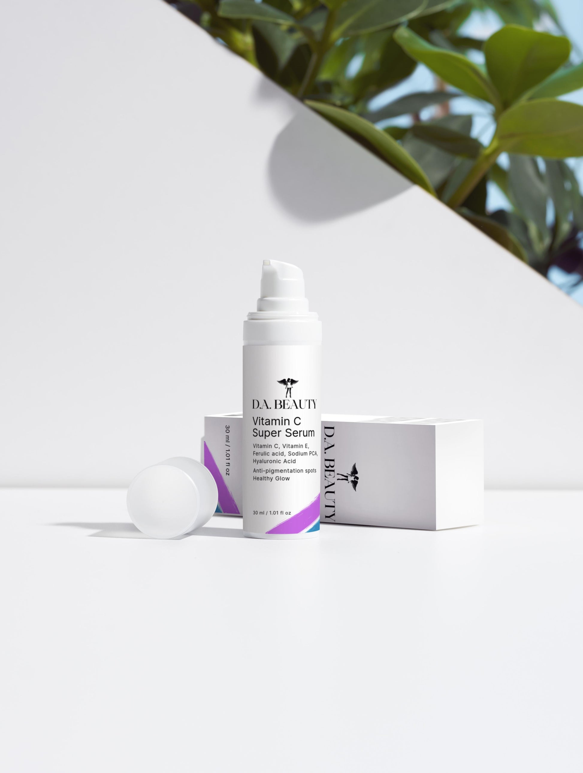 DA Beauty Vitamin C Super Serum on a white surface with a blurred green plant in the background